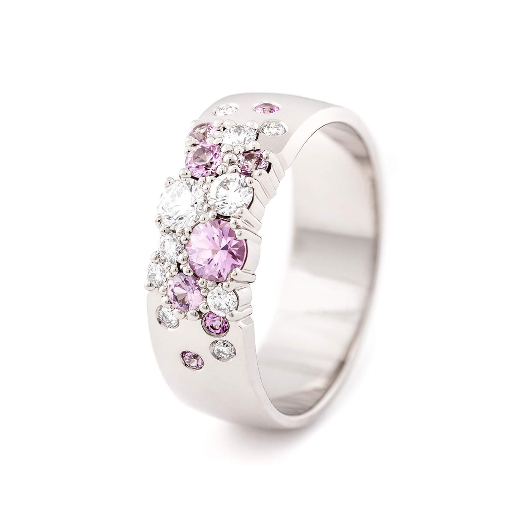 Different size light pink sapphires and white tw/vs diamonds in a Keto Meadow 6mm wide ring made in 18K white gold. Design by Jussi Louesalmi, Au3 Goldsmiths.