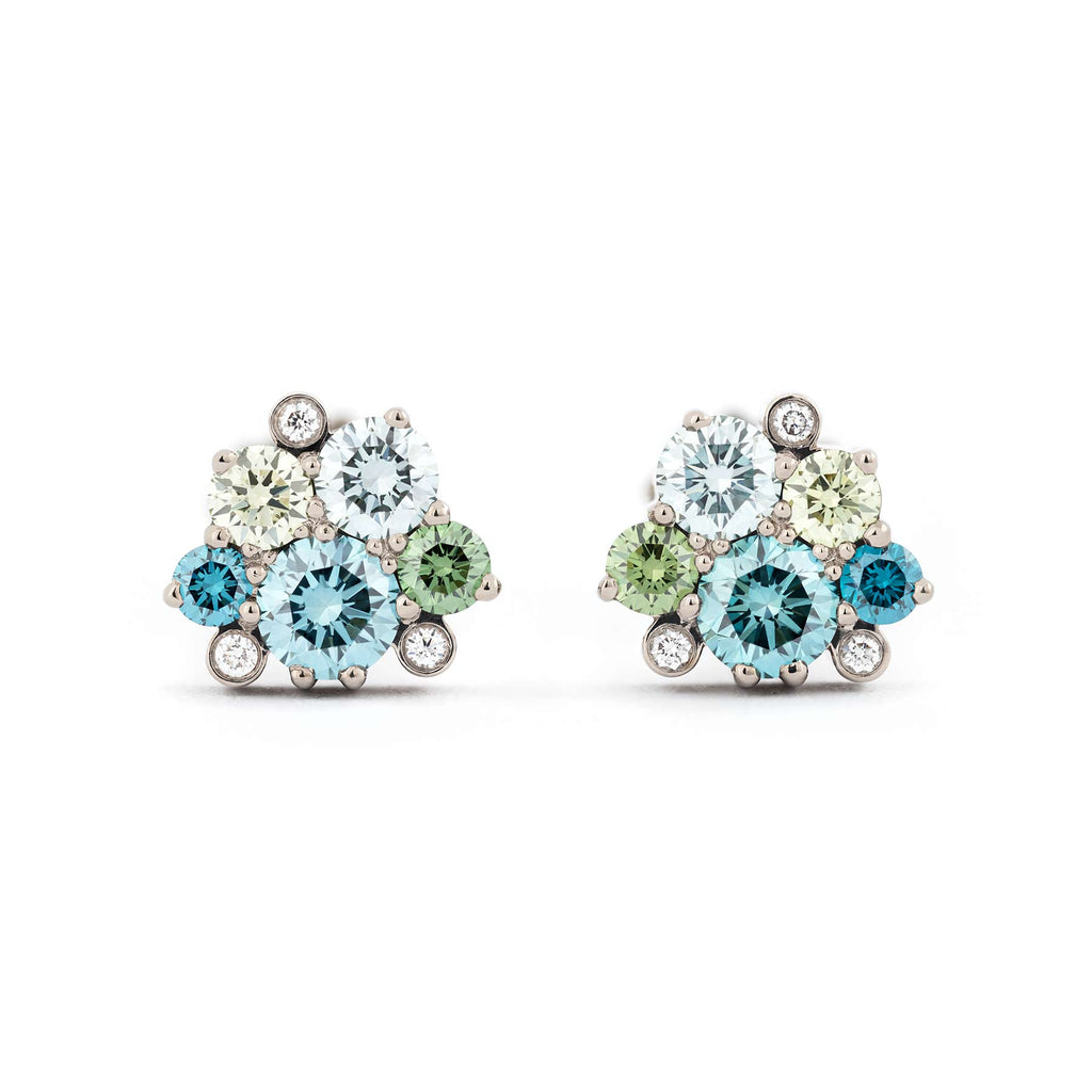 Different size green and turquoise color diamonds in addition to smaller white tw/vs diamonds in the Keto Meadow jewelry collection's stud earrings in 18K white gold. Design by Jussi Louesalmi, Au3 Goldsmiths.
