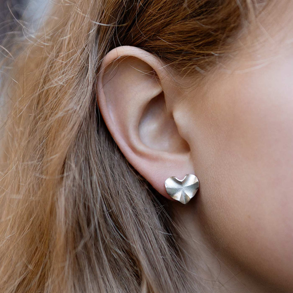 Model wearing a heart shaped Hauru earring made in 925 silver. Design by Anu Kaartinen, Au3 Goldsmiths.