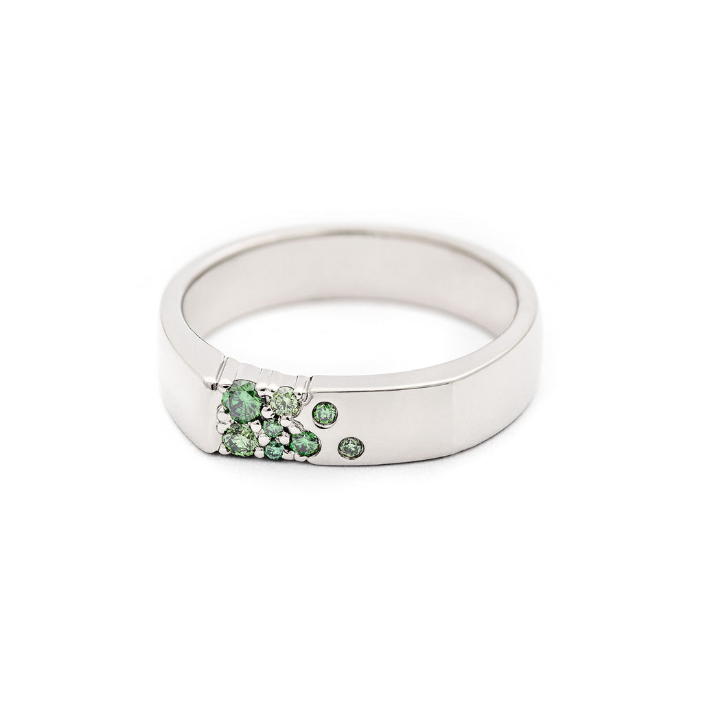 Unisex Kero ring in 18K white gold with asymmetrically placed green diamonds. Design by Jussi Louesalmi, Au3 Goldsmiths.