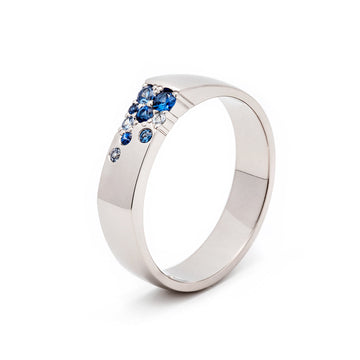 A sleek unisex Kero ring with multiple blue sapphire stones set in a smooth band, available in different precious metals. Design by Jussi Louesalmi, Au3 Goldsmiths.