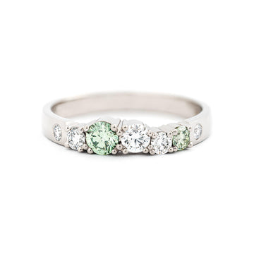 2,5mm wide row ring in recycled 18K white gold with different size white diamonds and two light green diamonds. Design Jussi Louesalmi, Au3 Goldsmiths.