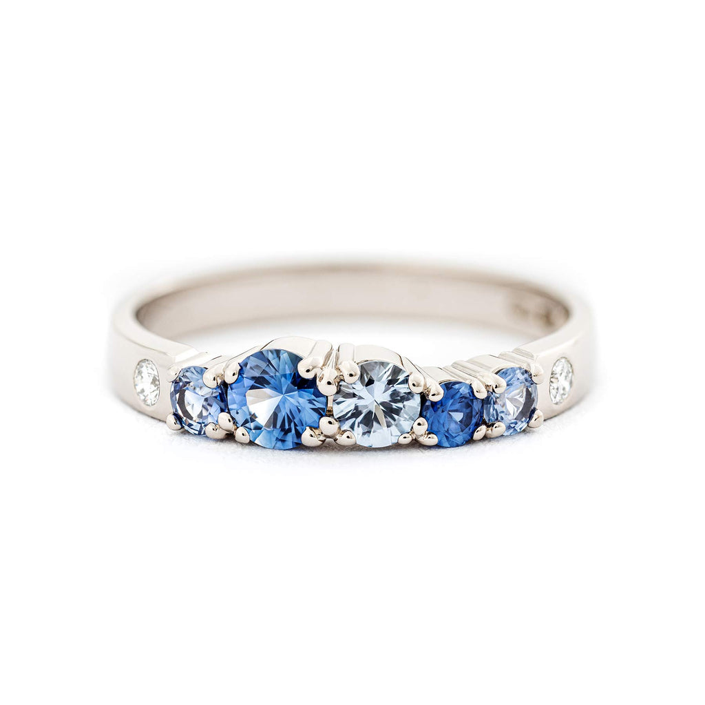 Different size blue sapphires and small white diamonds in a Keto Meado 2,5mm wide row ring. Design by Jussi Louesalmi, Au3 Goldsmiths.