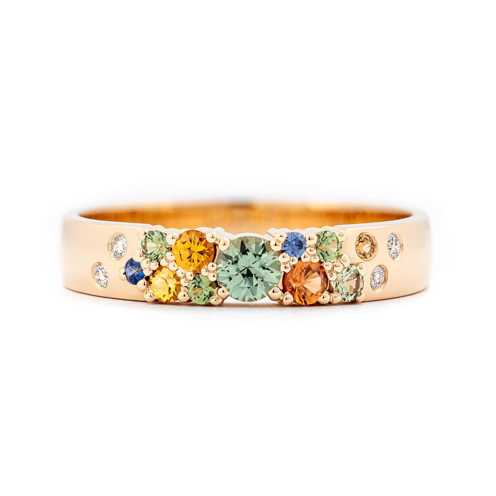 Different size sapphires in green, orange, yellow and blue colors together with white diamonds in a 4mm wide Keto Meadow ring. Design by Jussi Louesalmi, Au3 Goldsmiths.
