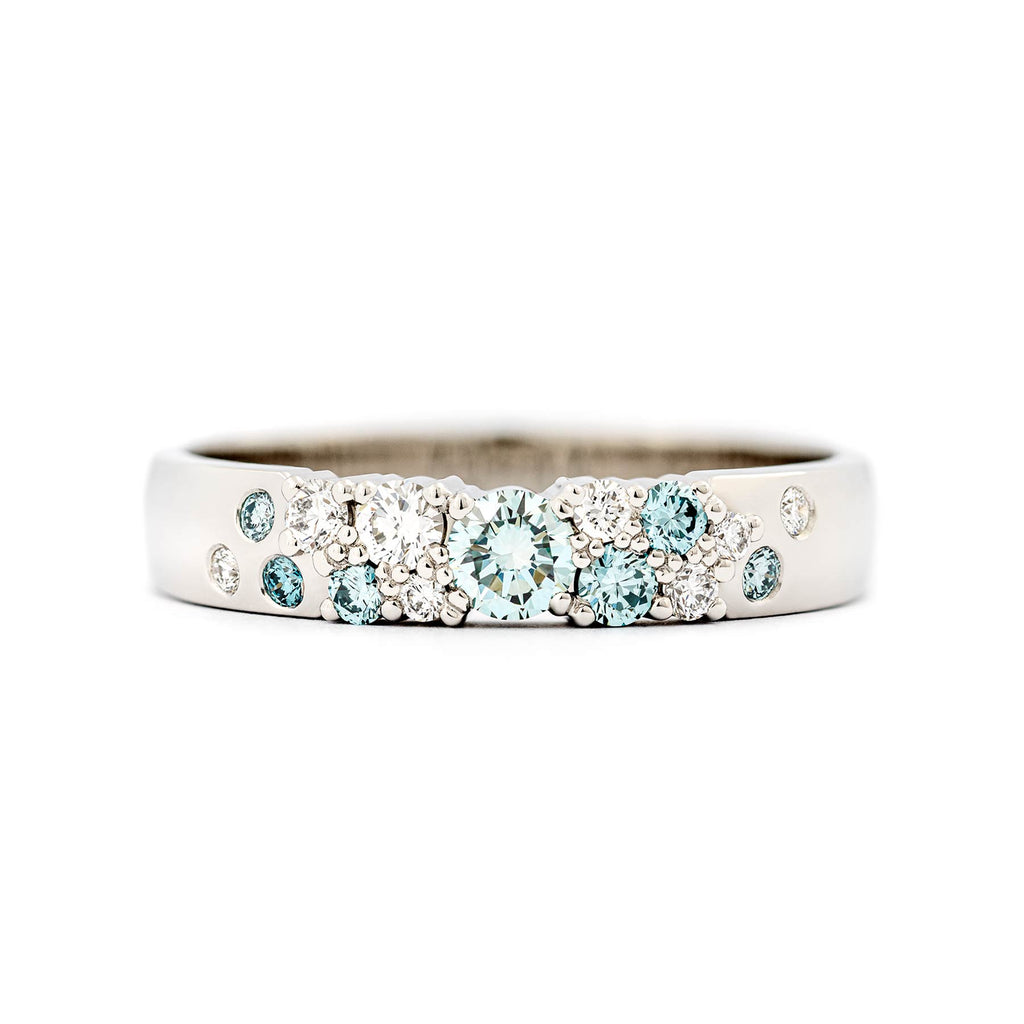 Keto Meadow 4mm wide ring in 750 white gold with asymmetrically placed turquoise Ice Blue diamonds and white diamonds. Design by Jussi Louesalmi, Au3 Goldsmiths.