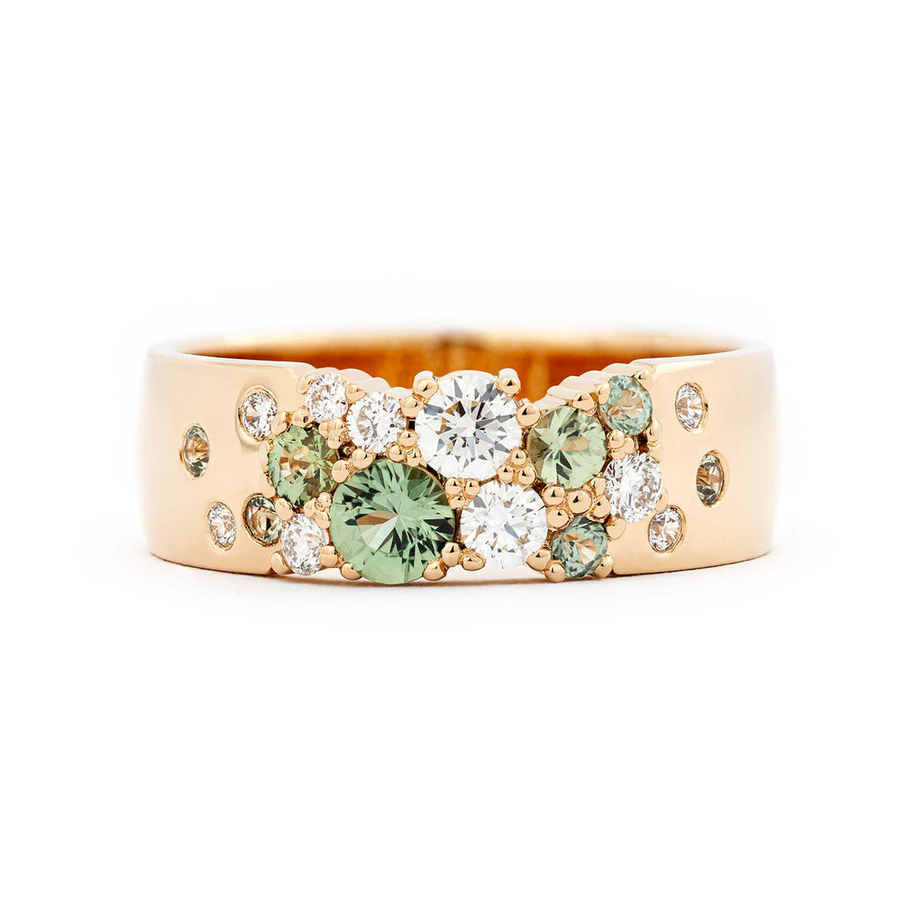 Asymmetrically placed light green sapphires and white tw/vs diamonds in a 6mm wide Keto meadow ring made in 18K yellow gold. Design by Jussi Louesalmi, Au3 Goldsmiths.