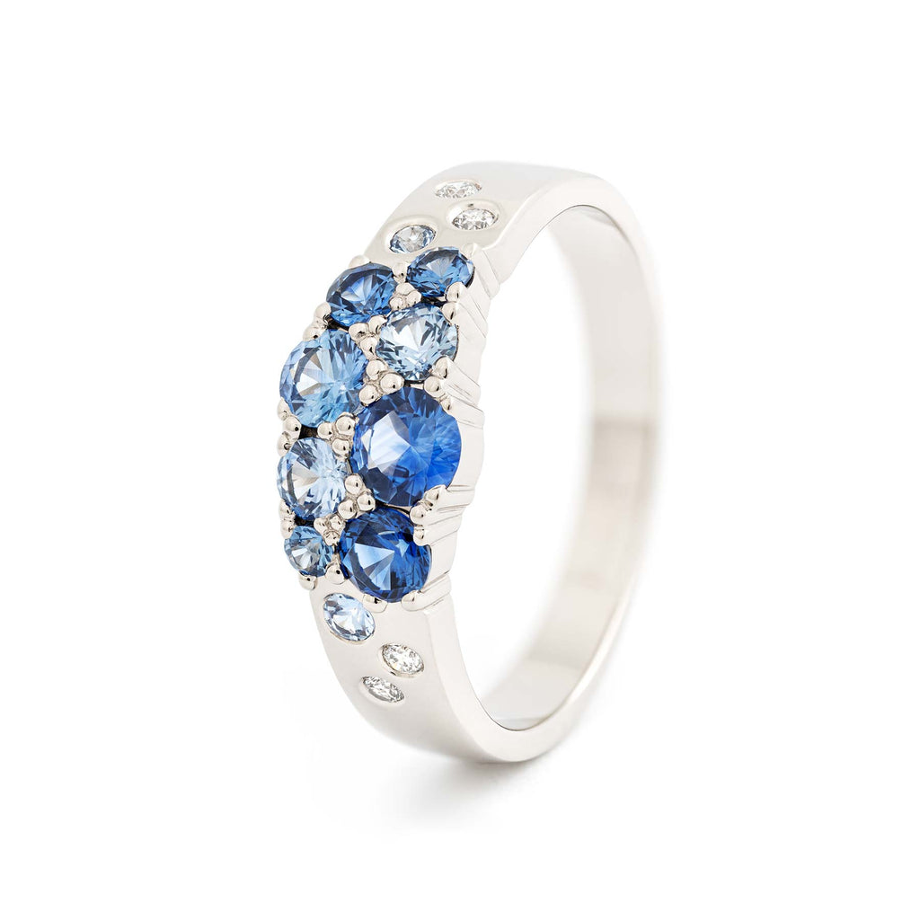 Blue sapphires and white diamonds in the narrowing band, crafted in 18K white gold. Design by Jussi Louesalmi, Au3 Goldsmiths. 