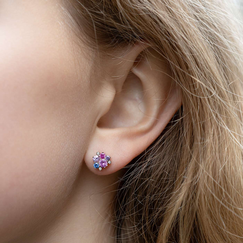 Model wearing a Keto Meadow earring made in 18K white gold with colorful sapphires and tw/vs diamonds. Design by Jussi Louesalmi, Au3 Goldsmiths.