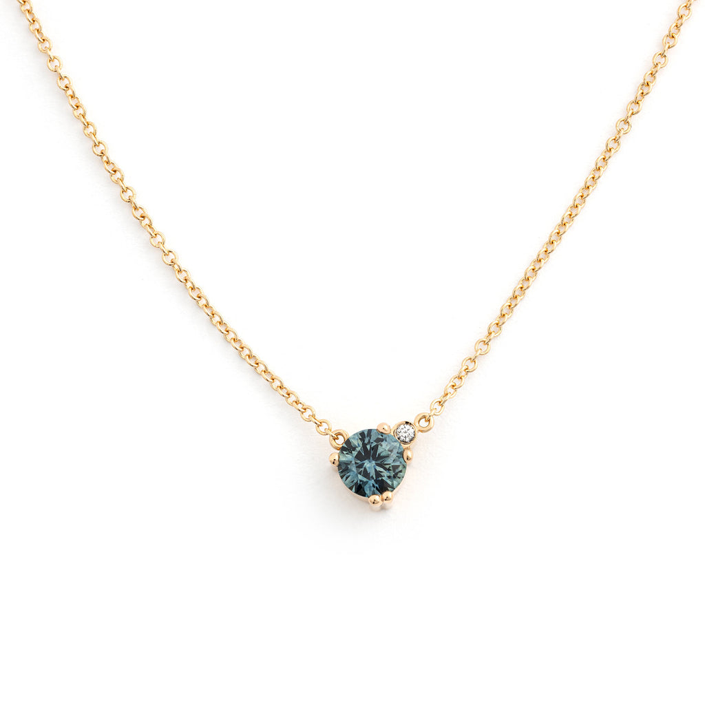 Larger greenish blue Montana sapphire and small white diamond in the Keto Meadow necklace crafted in recycled 18K yellow gold. Design by Jussi Louesalmi, Au3 Goldsmiths.