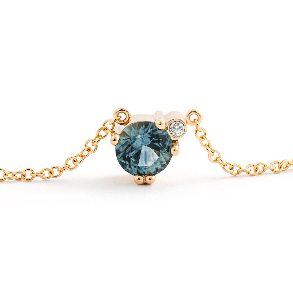 Larger greenish blue Montana sapphire and small white diamond in the Keto Meadow necklace crafted in recycled 18K yellow gold. Design by Jussi Louesalmi, Au3 Goldsmiths.