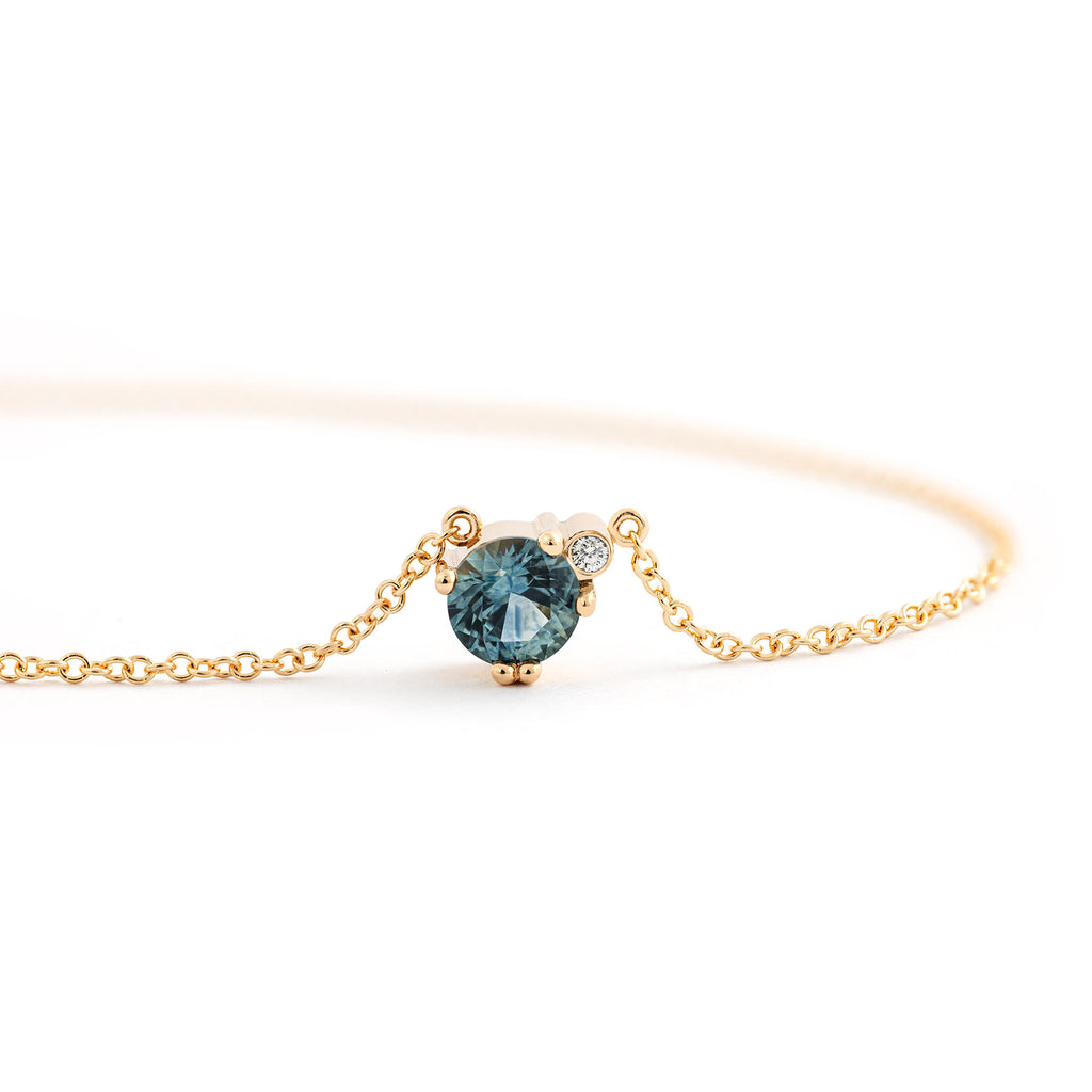Larger greenish blue Montana sapphire and small white diamond in the Keto Meadow necklace crafted in recycled 18K yellow gold. Design by Jussi Louesalmi, Au3 Goldsmiths.