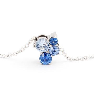 A close up of a necklace made in 18K white gold with four different size blue sapphires. Design Jussi Louesalmi, Au3 Goldsmiths.