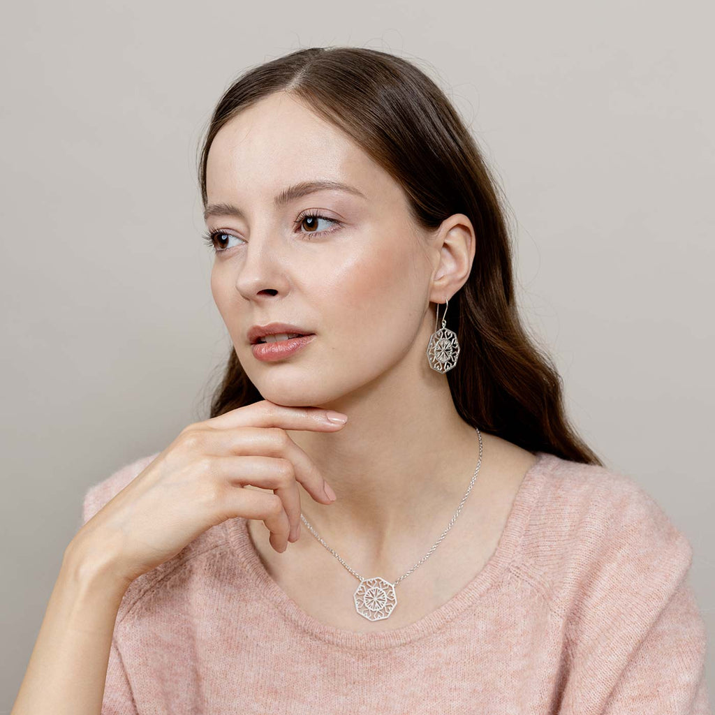 Model in a light pink blouse wearing geometric pattern Gems silver earrings and necklace. Design by Jussi Louesalmi, Au3 Goldsmiths.
