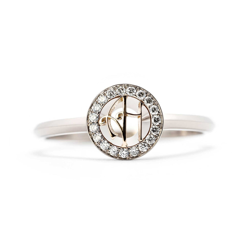 Grammi ring from the front angle: round monogram with two letters made in 750 yellow gold in the middle, circle of diamonds around the monogram. Material of the ring 750 white gold. Finalist of the Most beautiful ring of the year 2021. Design Tero Hannonen, Au3 Goldsmiths.