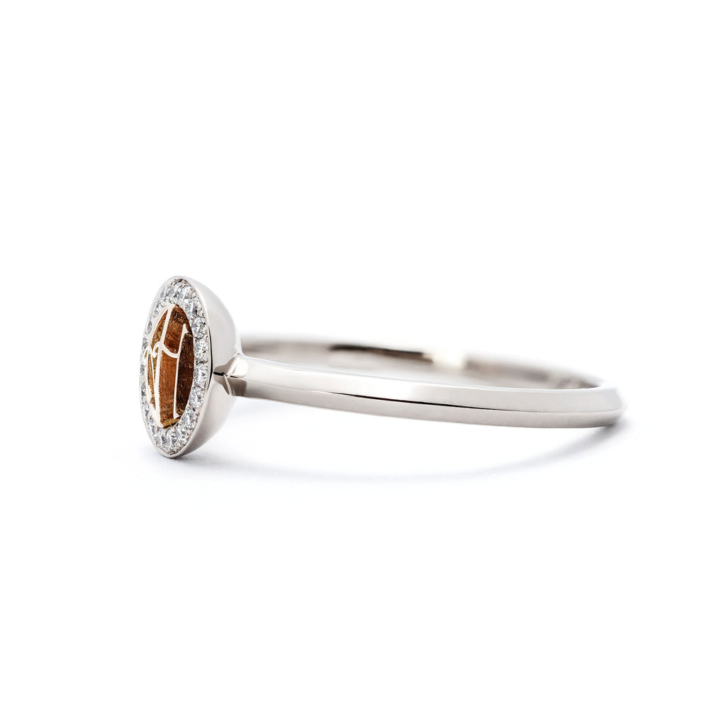 Grammi ring: round monogram with two letters made in 750 yellow gold in the middle, circle of diamonds around the monogram. Material of the ring 750 white gold. Photo from the side. Finalist of the Most beautiful ring of the year 2021. Design Tero Hannonen, Au3 Goldsmiths.