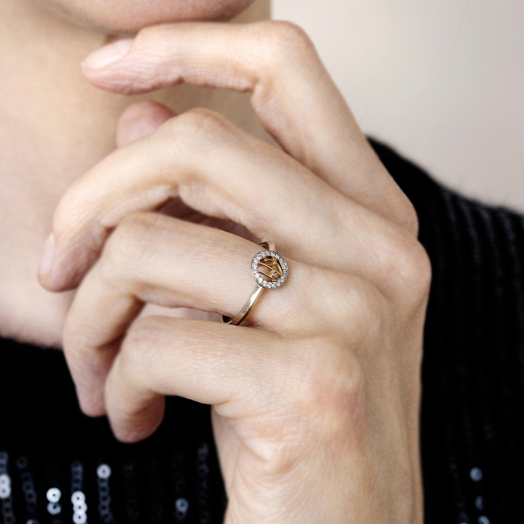 Model wearing a Grammi ring: round monogram with two letters in the middle of a circle of diamonds. Design by Tero Hannonen, Au3 Goldsmiths.