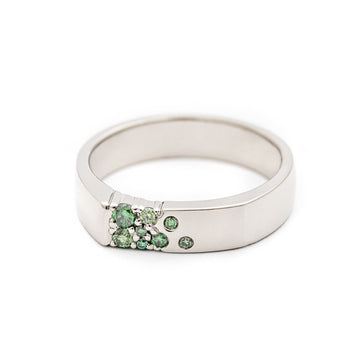 Unisex Kero white gold ring with asymmetrically placed green diamonds. Design by Jussi Louesalmi, Au3 Goldsmiths.