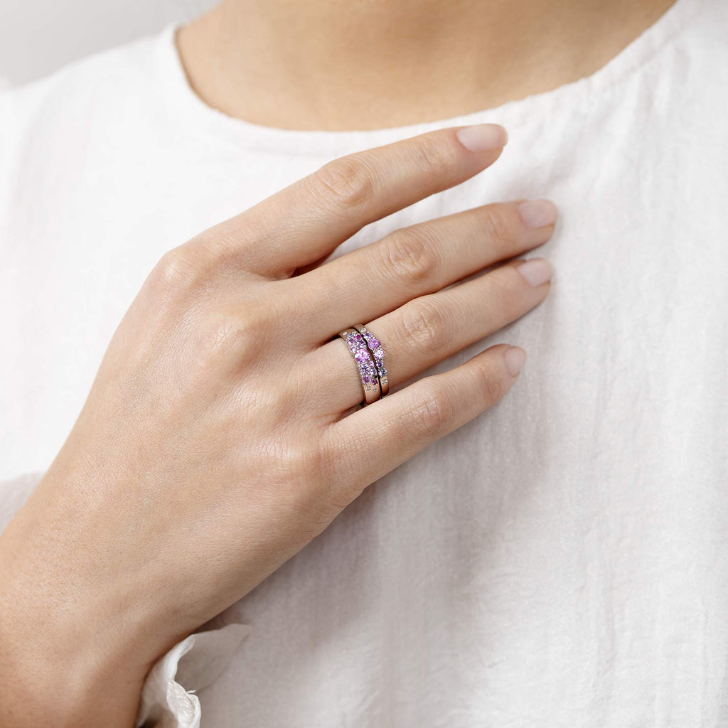 Model wearing a 4mm and 2mm wide Keto Meadow rings. The rings have pink, purple and blue sapphires and white diamonds. Design by Jussi Louesalmi, Au3 Goldsmiths.