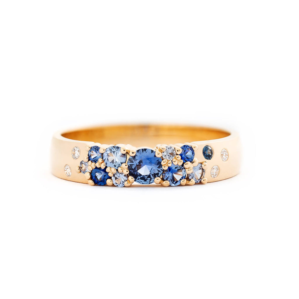 Keto Meadow 4mm wide ring in glowing 750 yellow gold, with different size white diamonds and blue sapphires placed asymmetrically. Design by Jussi Louesalmi, Au3 Goldsmiths.