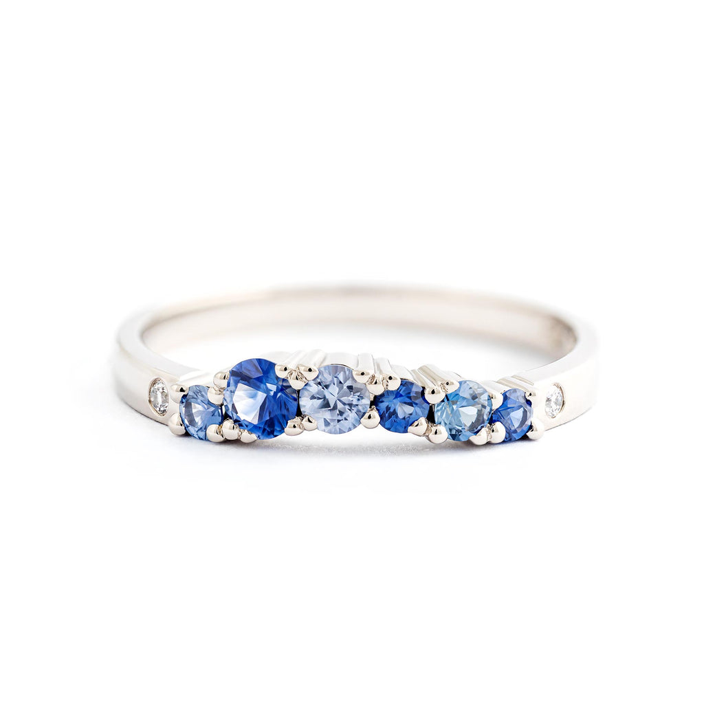 Keto Meadow Arc ring with 6 blue sapphires and 2 white diamonds. The ring suits well next to a Keto Meadow narrowing ring. Design by Jussi Louesalmi, Au3 Goldsmiths.