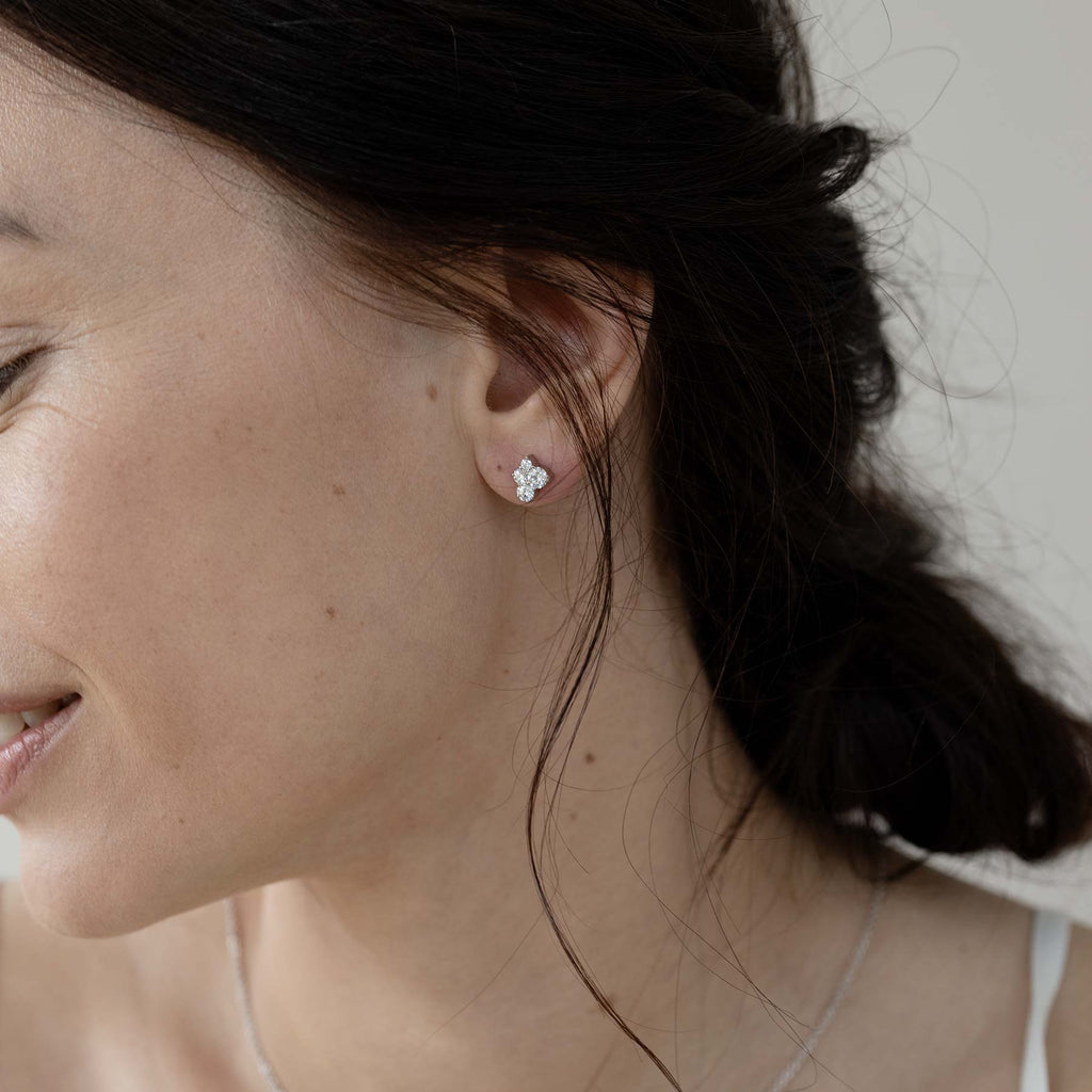 A dark haired model wearing a Keto Meadow earring with 4 white diamonds. Design by Jussi Louesalmi, Au3 Goldsmiths.