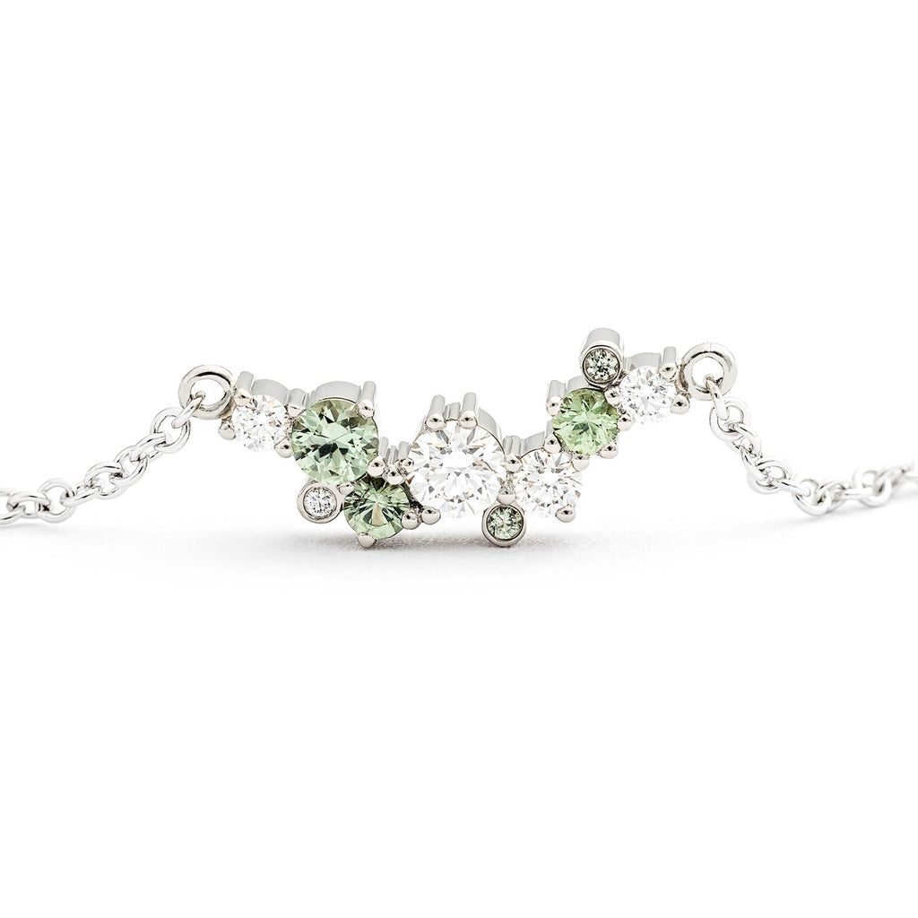 Different size and asymmetrically placed green sapphires and white tw/vs diamonds in a Keto Meadow Spring Crown necklace, design by Jussi Louesalmi, Au3 Goldsmiths