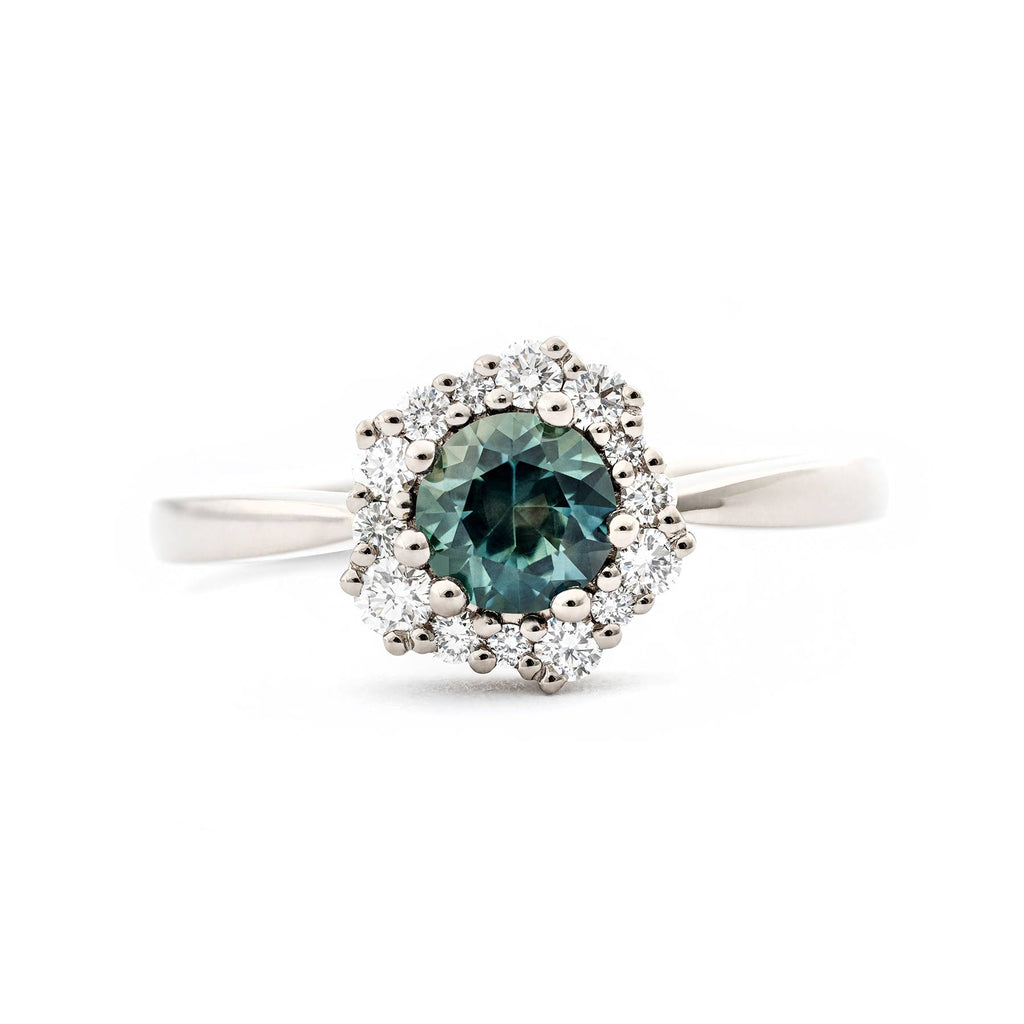 Vibrant green Montana sapphire in a Lilibet ring, surrounded by smaller different size asymmetrically placed white diamonds. Design by Jussi Louesalmi, Au3 Goldsmiths