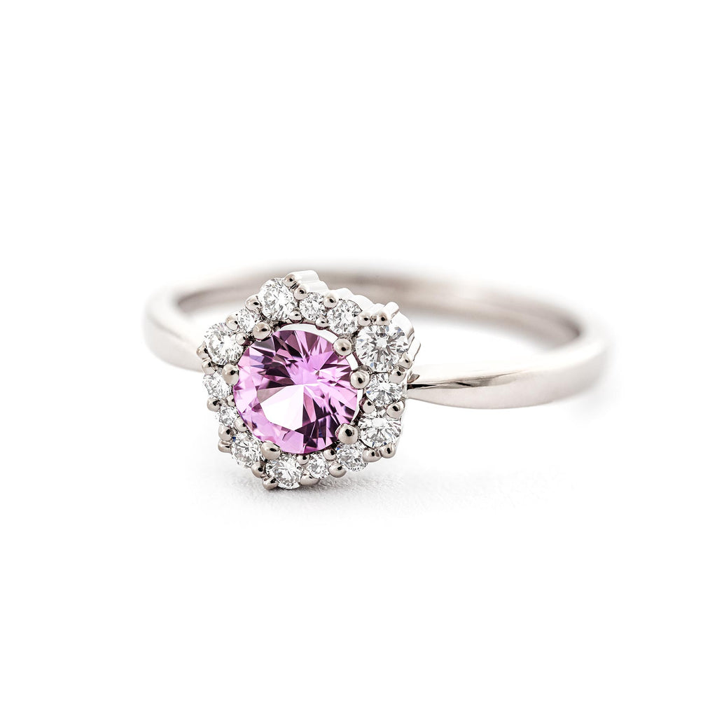 Glamorous Lilibet ring with a large sapphire in light pink color, surrounded by different size white tw/vs diamonds. Design by Jussi Louesalmi, Au3 Goldsmiths