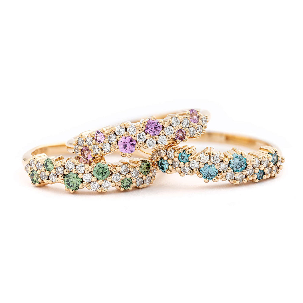 A pile of colorful MyWay rings with drops of pink sapphires, green, blue and white diamonds. Design by Jussi Louesalmi, Au3 Goldsmiths.