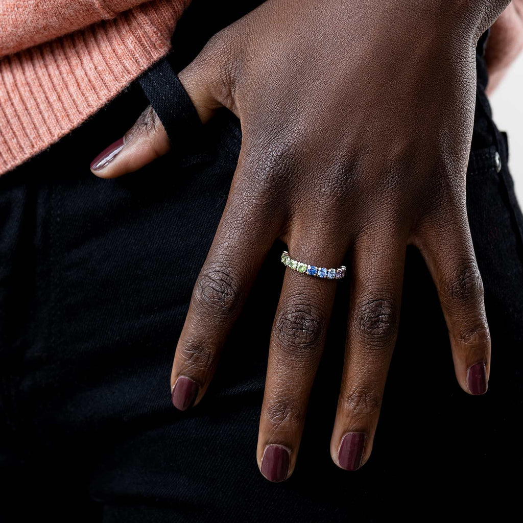 Model wearing a Rainbow ring with colorful sapphires circulating around the ring with gliding color tones, design by Jussi Louesalmi, Au3 Goldsmiths